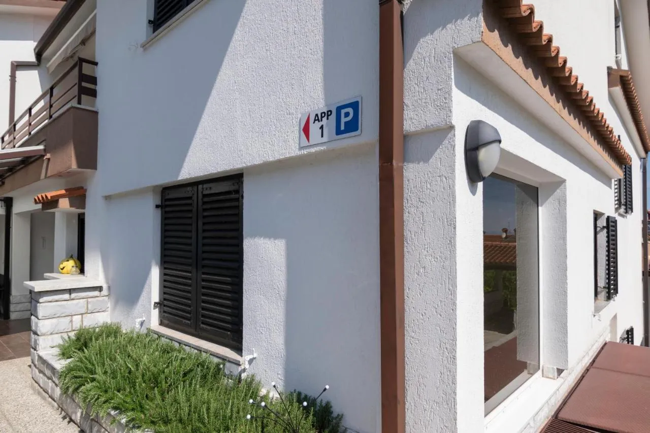 Stranski vhod v hišo z oznako za apartma in parkirišče